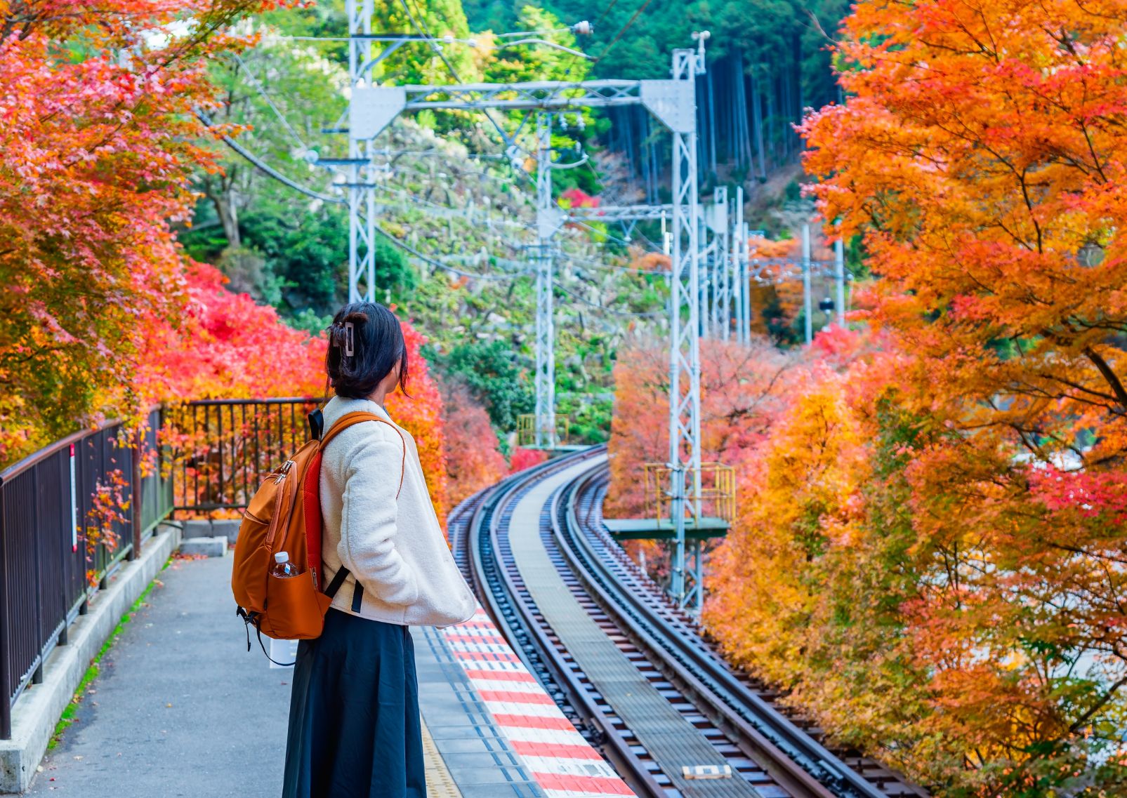 Chica esperando el tren en Japón en otoño