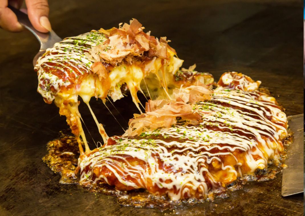 Tortita salada japonesa, conocida como okonomiyaki, hecha a la parrilla.