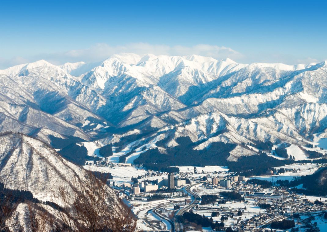 Ciudad rodeada de montañas nevadas bajo cielo despejado.