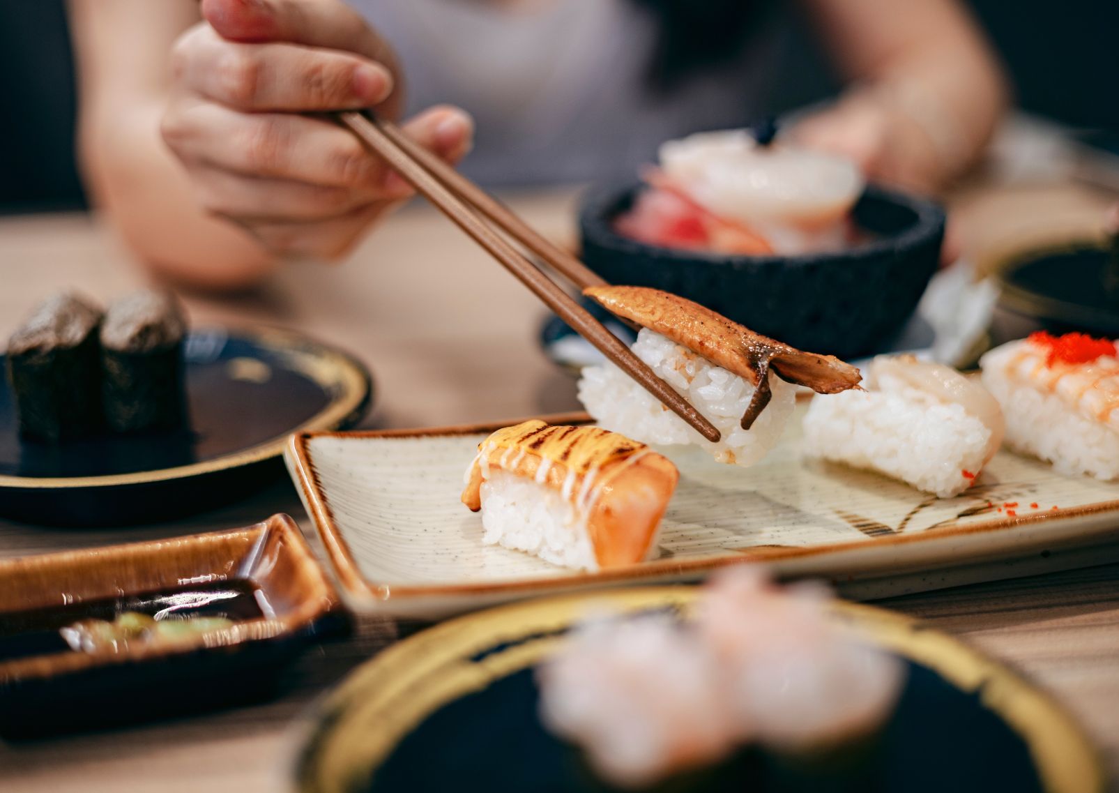 Mujer japonesa cogiendo un nigiri sushi con palillos