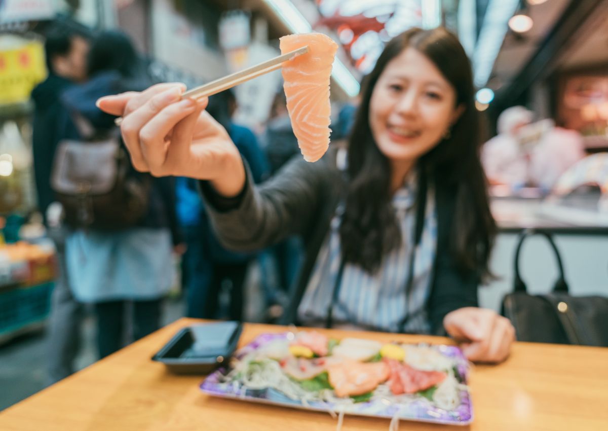 Chica comiendo sushi en el Mercado Kuromon, Osaka