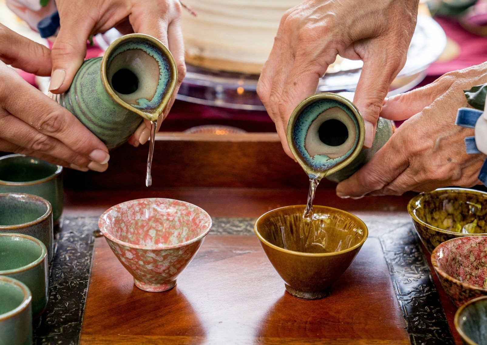 Personas sirviendo sake japonés en vasos tradicionales