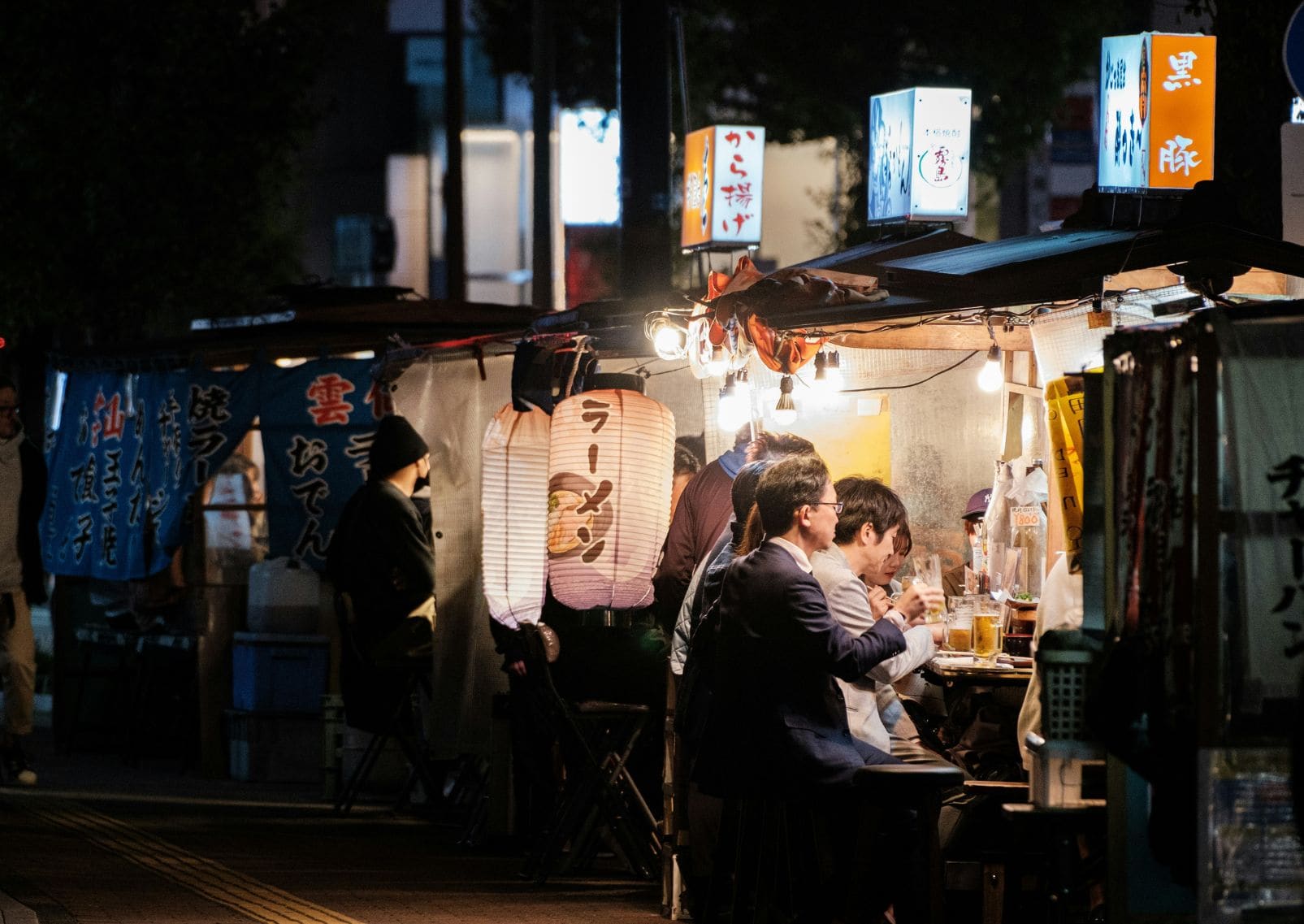 Grupo de personas sentados en los puestos de comida de Fukuoka llamados Yatai