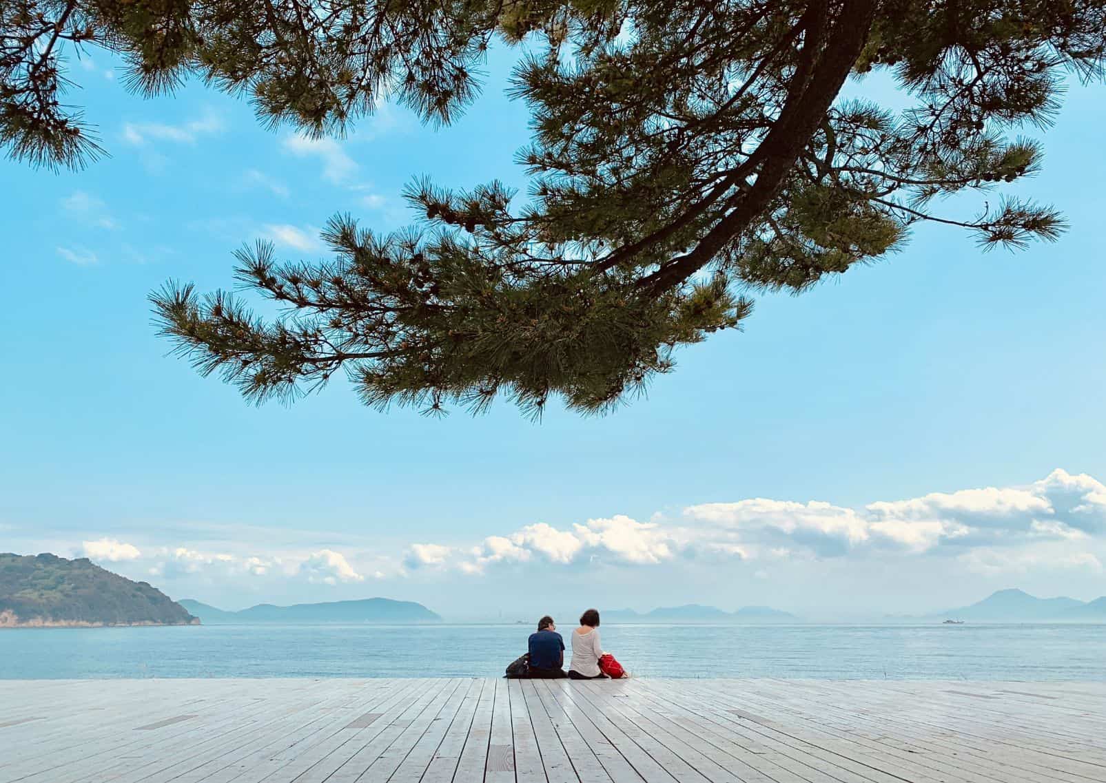 Gente sentada en la soleada costa de Naoshima