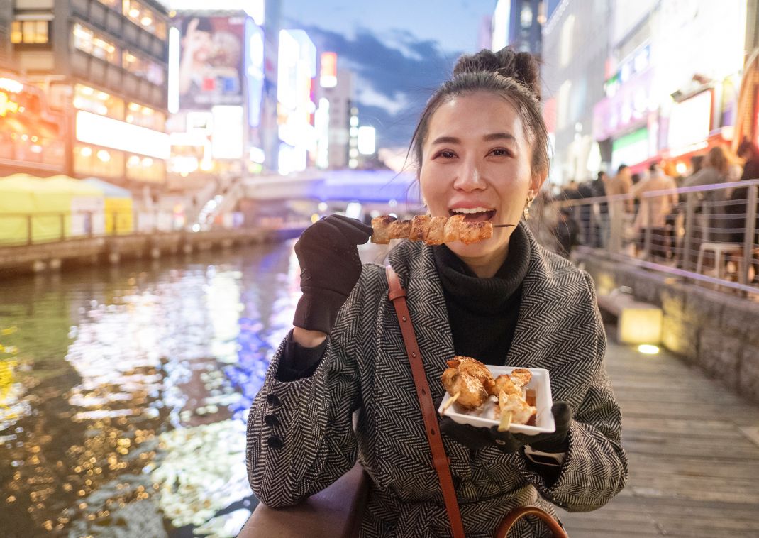 Mujer japonesa disfrutando de auténtica comida callejera en Osaka