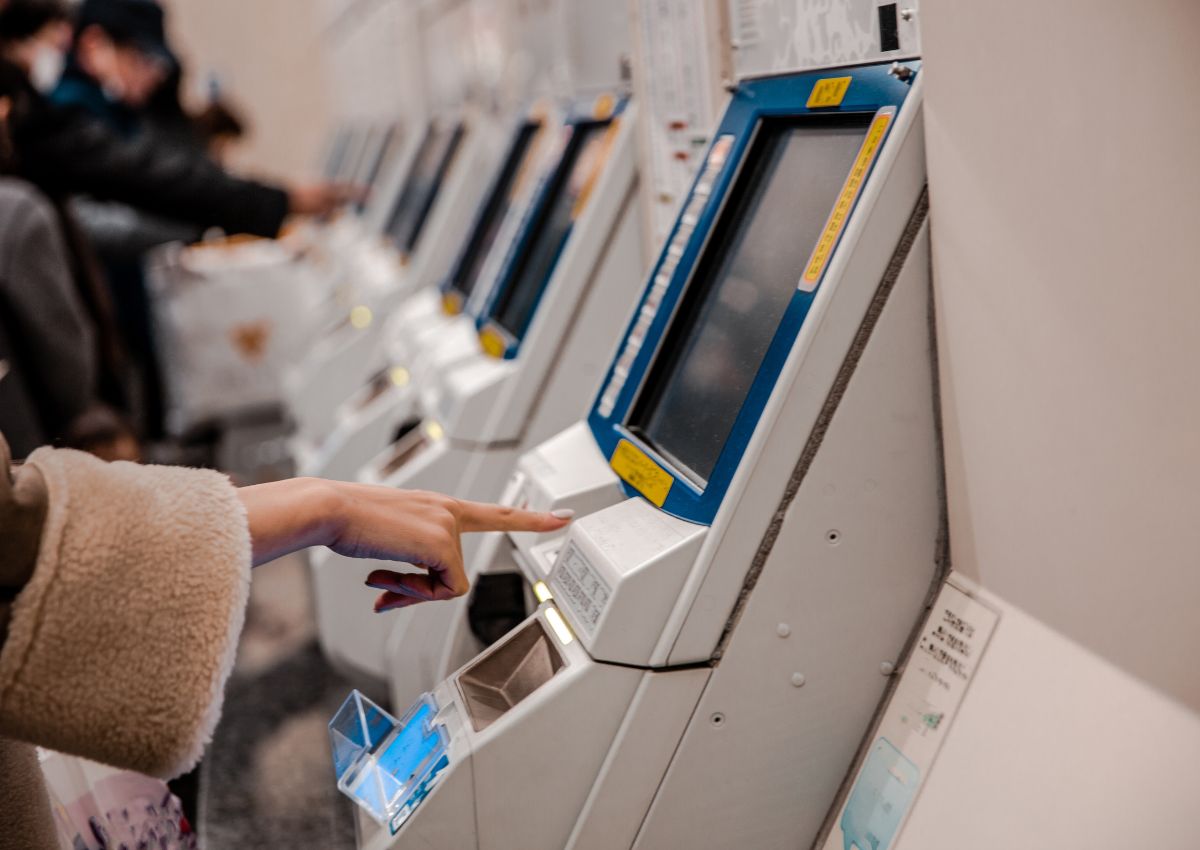 Mujer comprando billetes de tren en la máquina