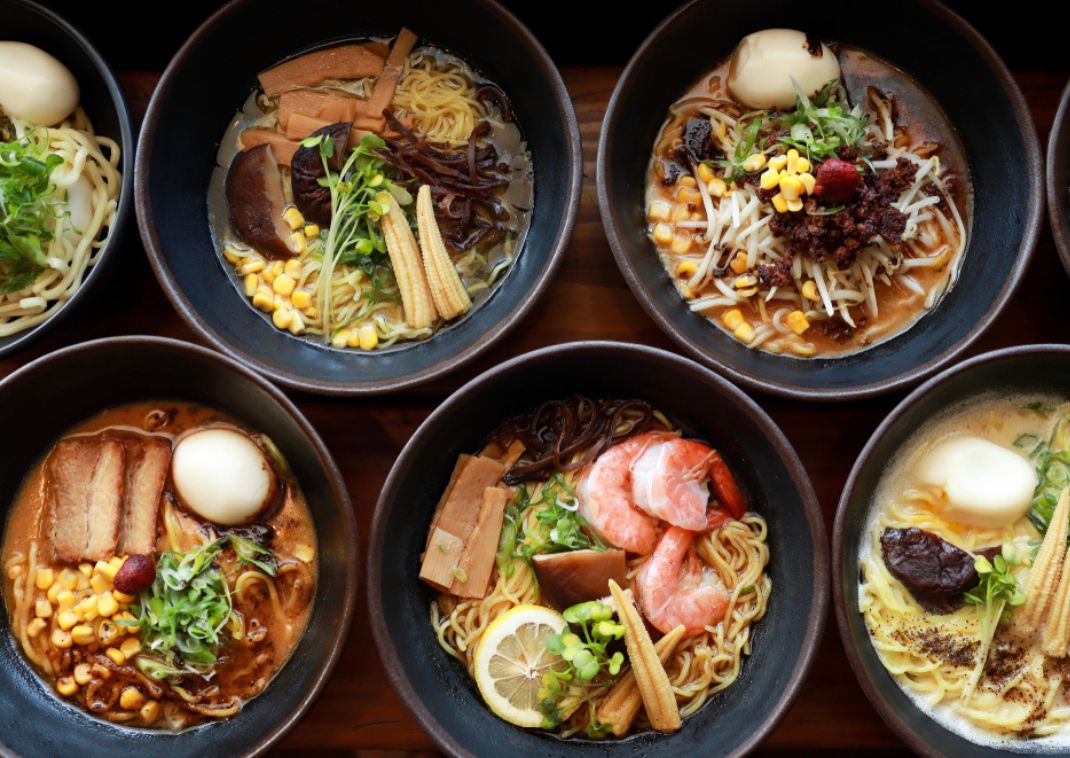 Tazones variados de ramen japonés con diferentes ingredientes como huevos cocidos, maíz, camarones, elote baby y verduras.