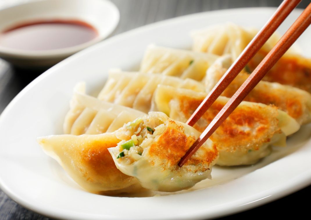 Deliciosos gyozas japonesas, sostenidos por un par de palillos
