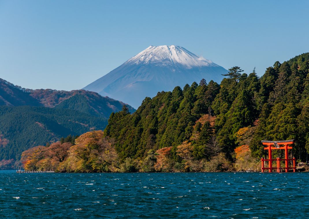 Monte Fuji y un gran torii rojo en el lago Ashinoko, sobre un fondo azul claro. Vista de Hakone en Japón