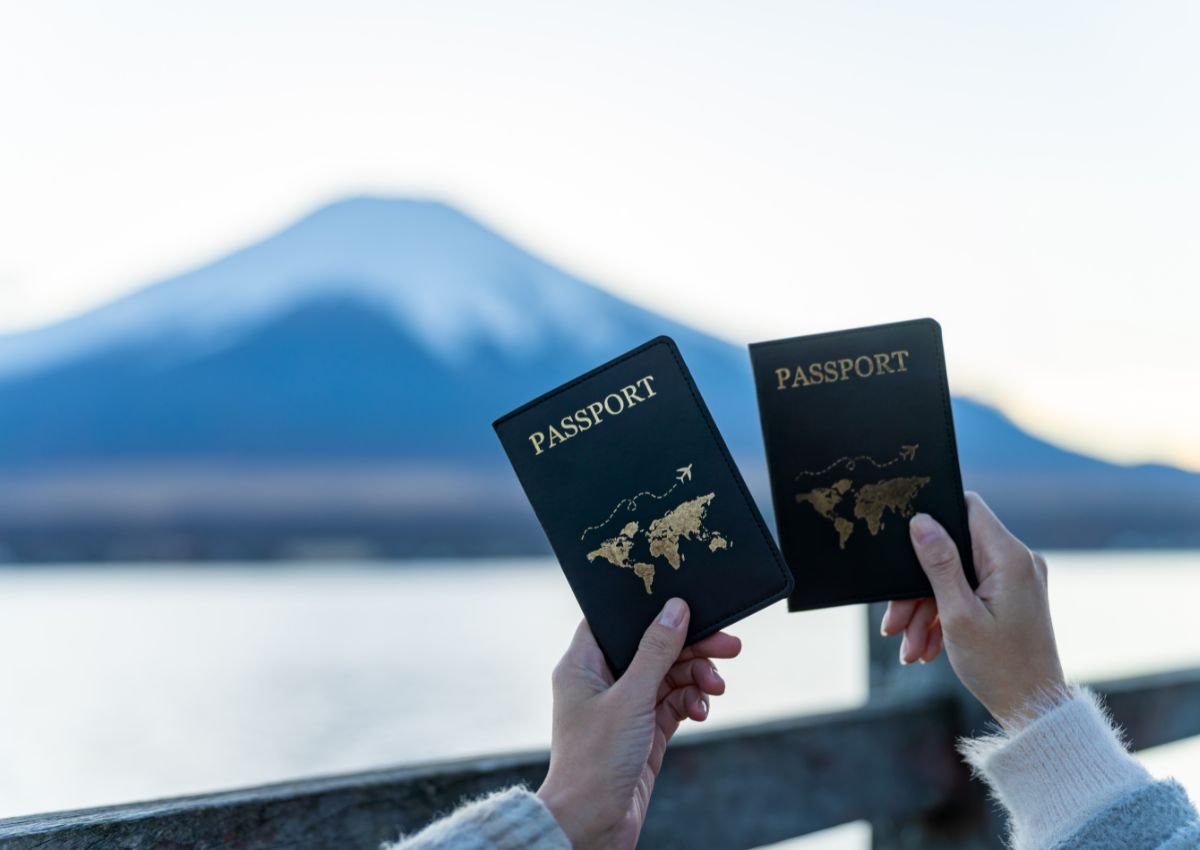 Manos de mujer sosteniendo un pasaporte frente al monte Fuji