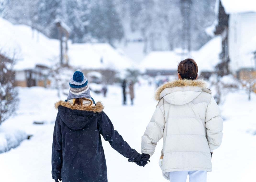 Pareja caminando de la mano en el pueblo invernal de Ouchi-juku, Japón