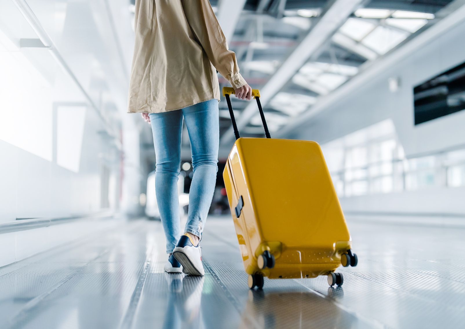Mujer llegando a la terminal del aeropuerto con su equipaje