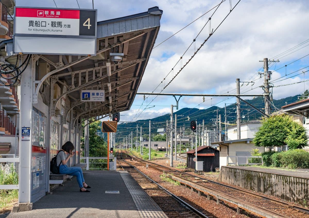 Mujer asiática sentada en la estación y esperando a su tren que llega con retraso