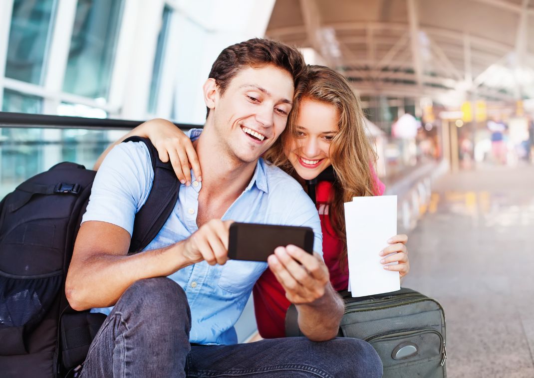 Pareja tomándose selfies en el aeropuerto.