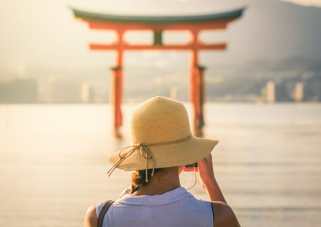 Chica fotografiando la puesta de sol en la isla de Miyajima, Japón.