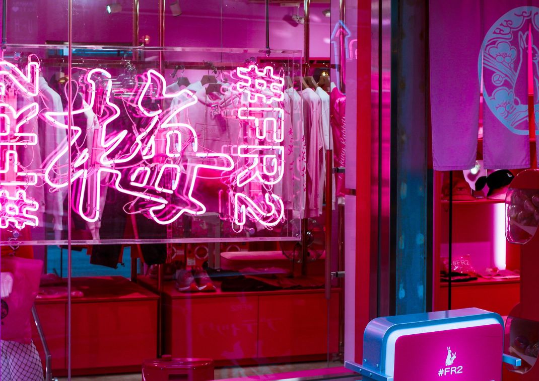 Letrero japonés de neón rosa en la ventana de una boutique de moda moderna con ropa y accesorios exhibidos en el interior