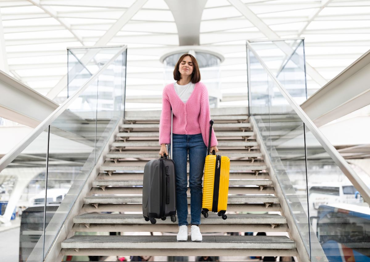 Mujer cargando las maletas escaleras abajo