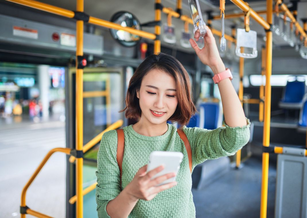 Mujer mirando su teléfono mientras viaja en autobús en Japón