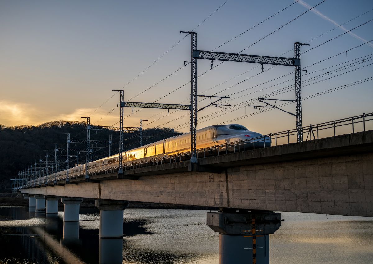 Mano que sostiene un Japan Rail Pass delante de un tren shinkansen en Japón