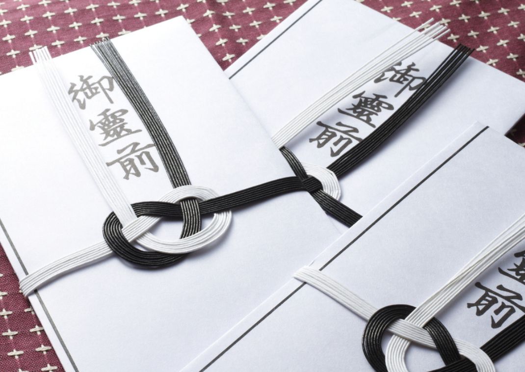 Primer plano de sobres tradicionales japoneses de condolencias con cordones negros y blancos y caracteres kanji, usados para ofrendas funerarias.