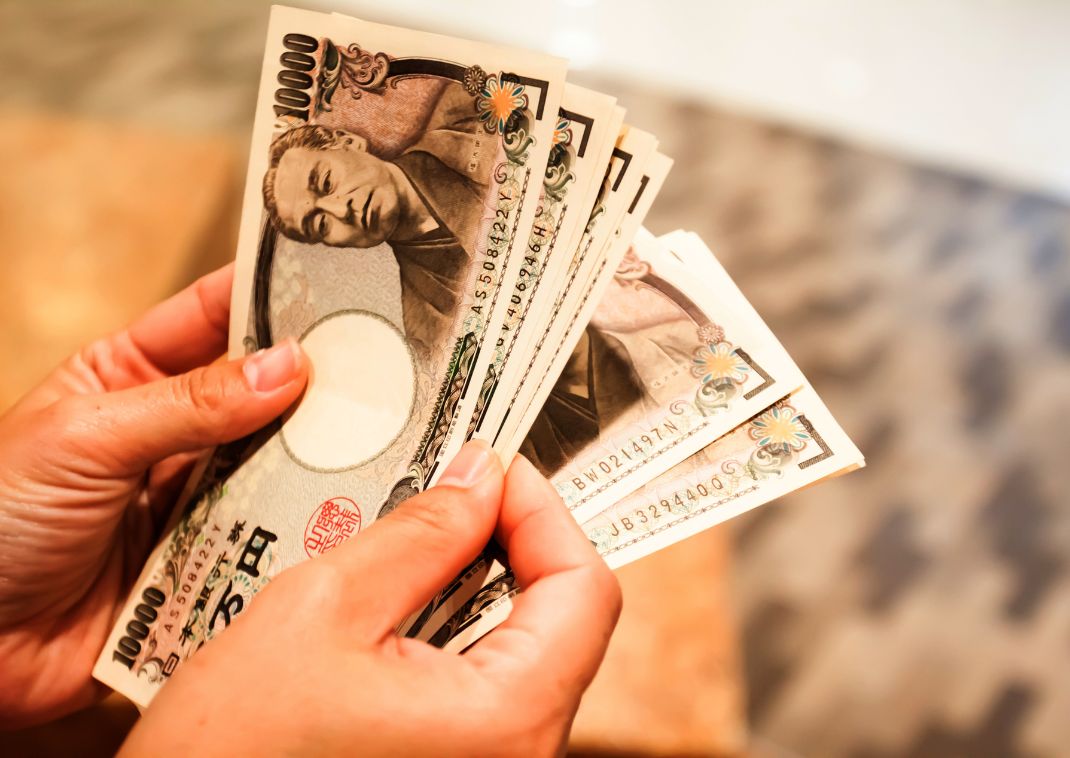 Persona abanicando una gran suma de billetes de banco japoneses en yenes 