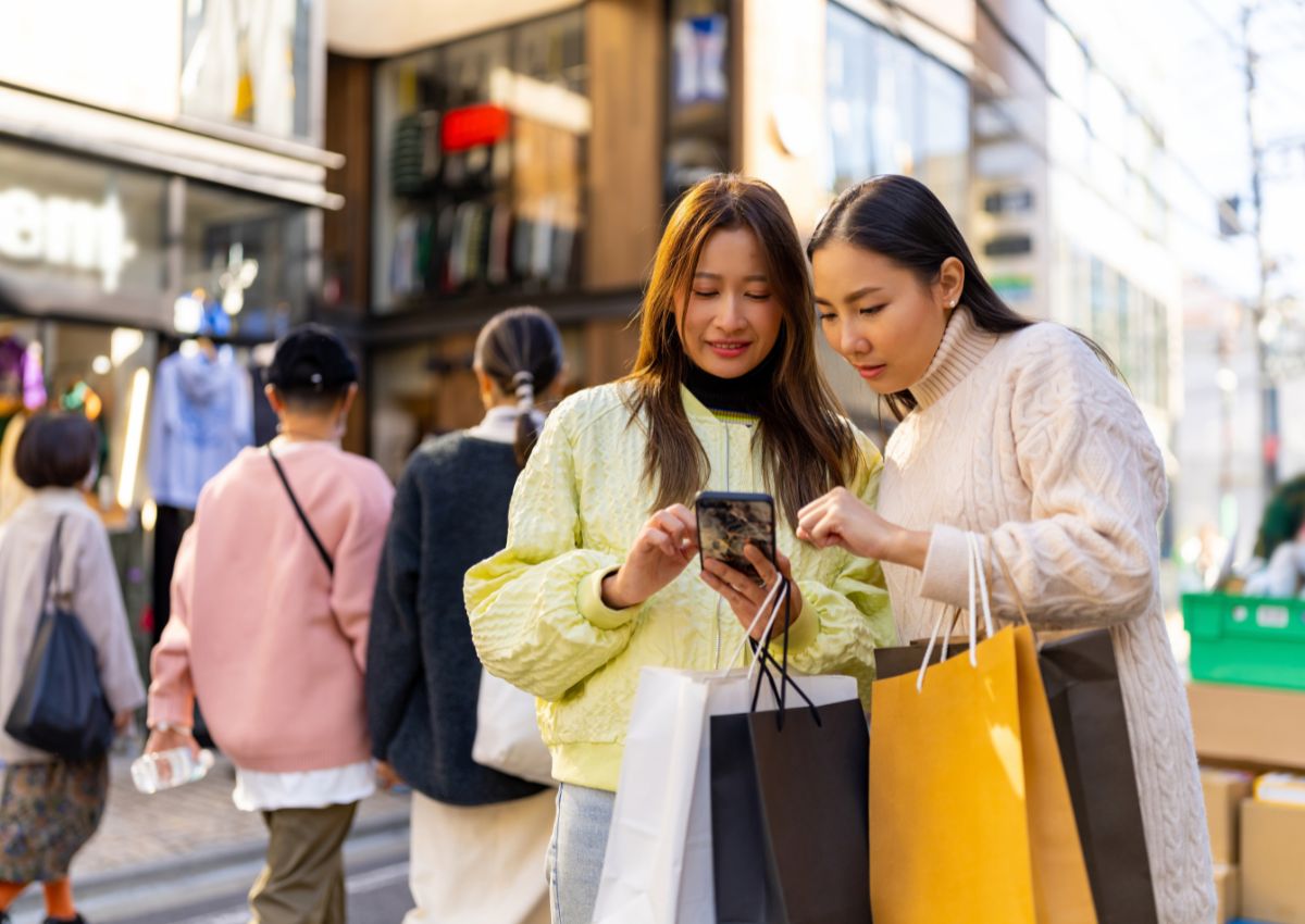Mujeres turistas en Japón que utilizan el móvil mientras hacen compras