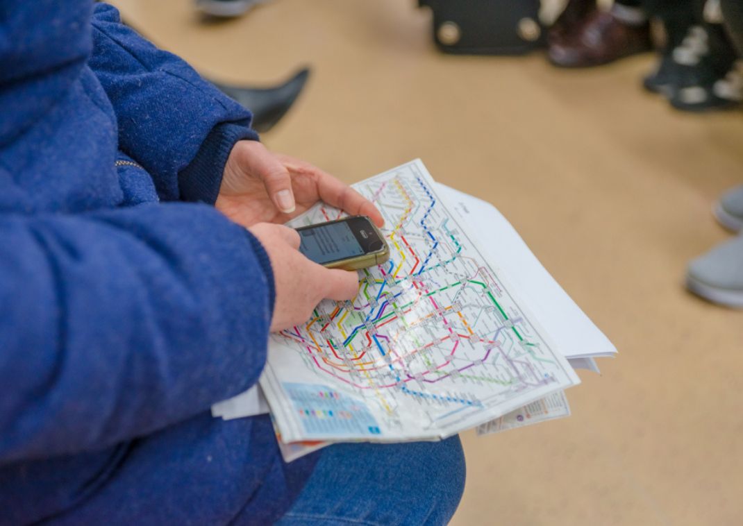 Persona con mapa del metro y teléfono móvil en la mano.