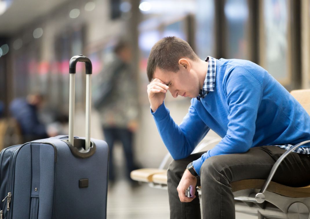 Un hombre en el aeropuerto con equipaje, apariencia decepcionada porque ha perdido su vuelo