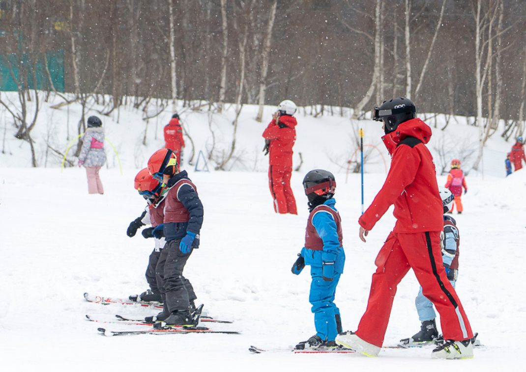 Niños aprendiendo a esquiar con instructor en la nieve