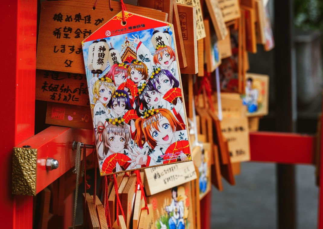 Placas ema de madera en un santuario japonés, con una ilustración colorida de personajes de anime con trajes tradicionales de festival