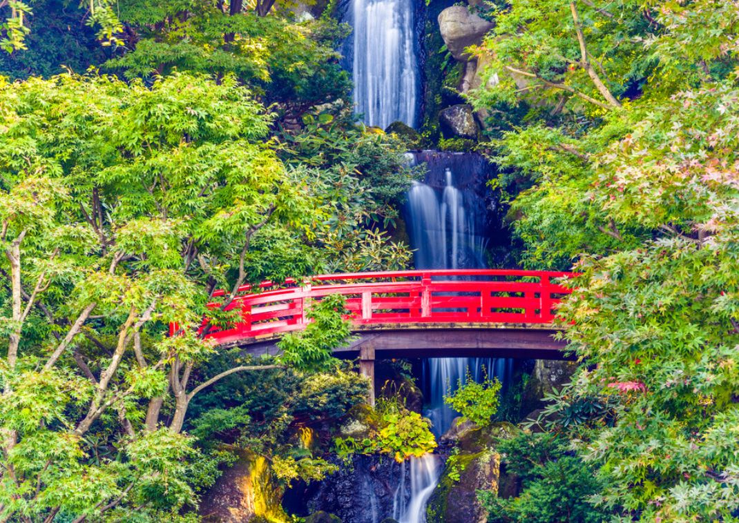 Escena de una cascada en Japón con un puente rojo