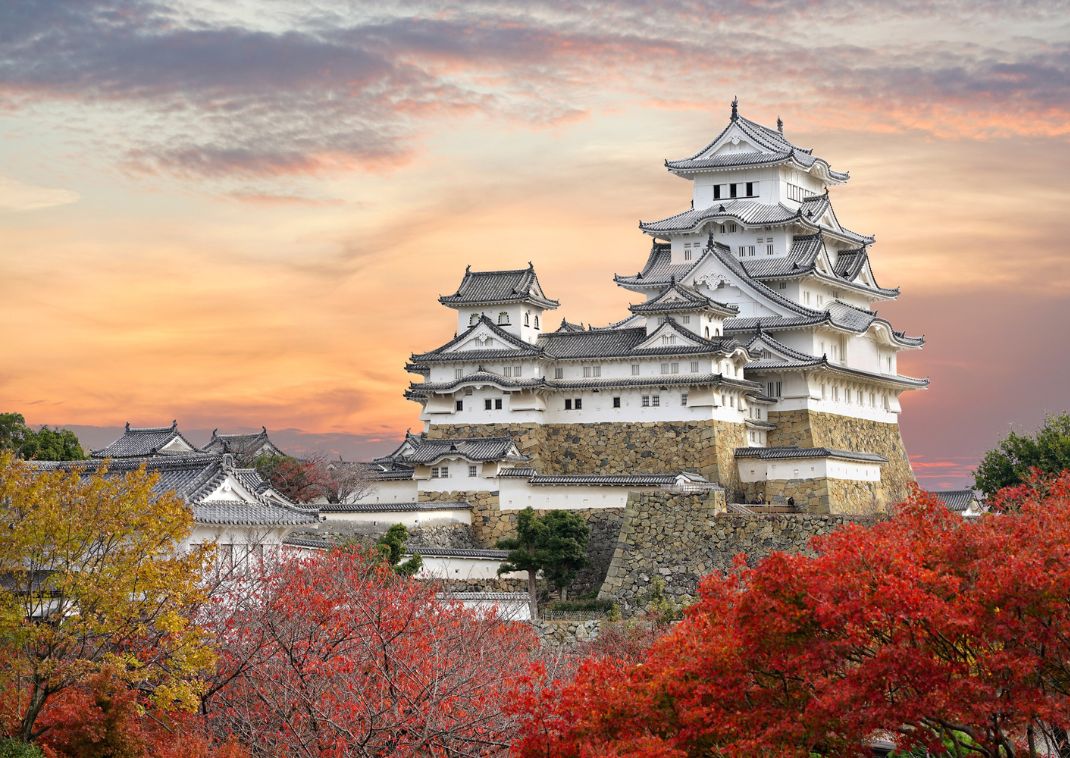 Castillo de Himeji, con hojas rojizas de arce, al atardecer. Japón