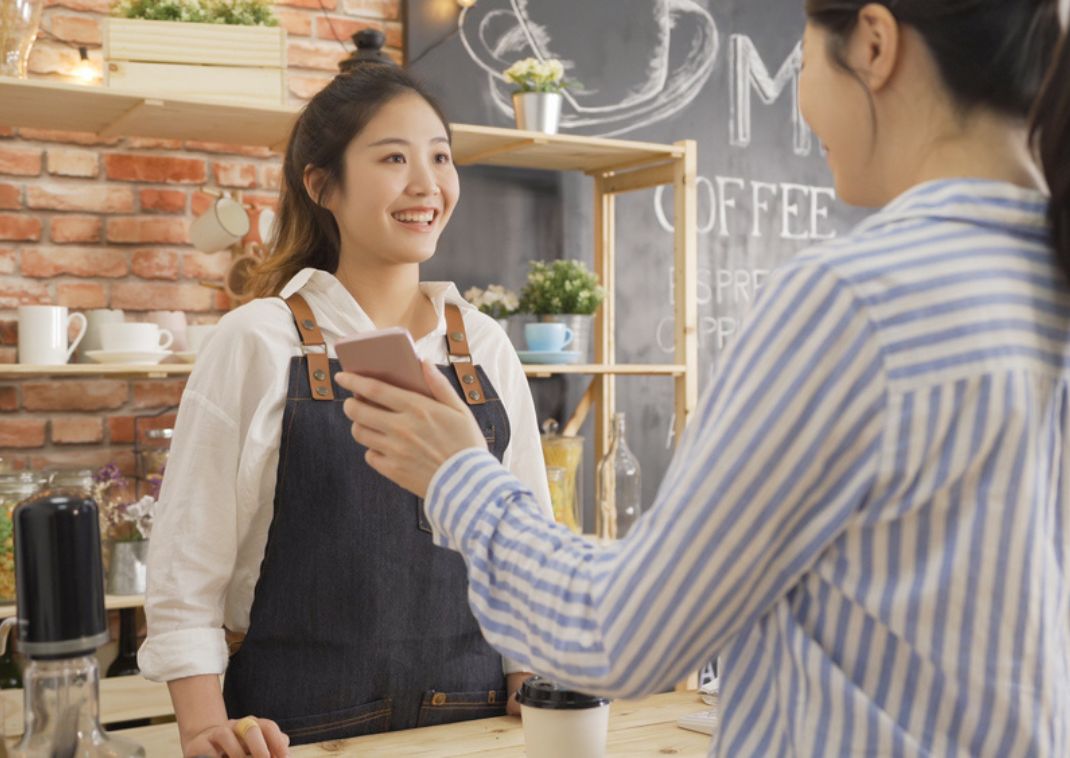 Barista asiática atendiendo a una clienta