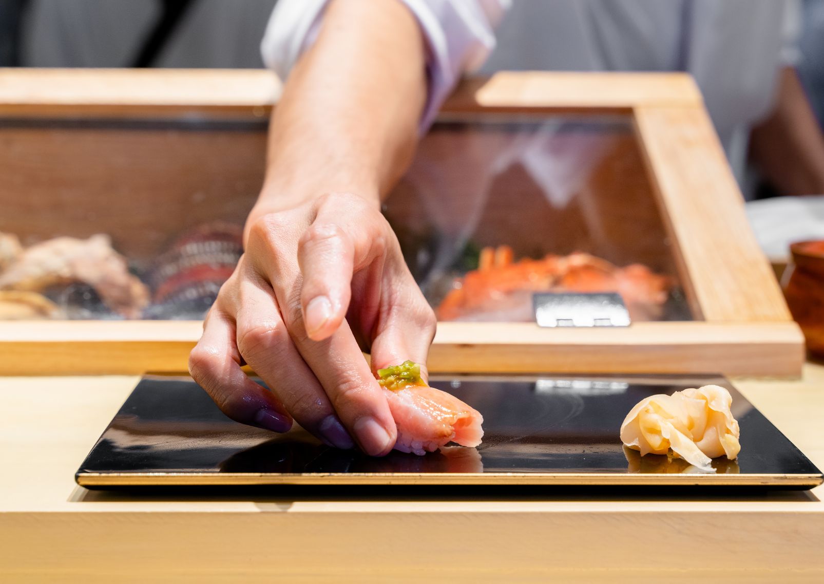 Chef japonés de sushi sirviendo un nigiri sushi recién preparado en experiencia Omakase