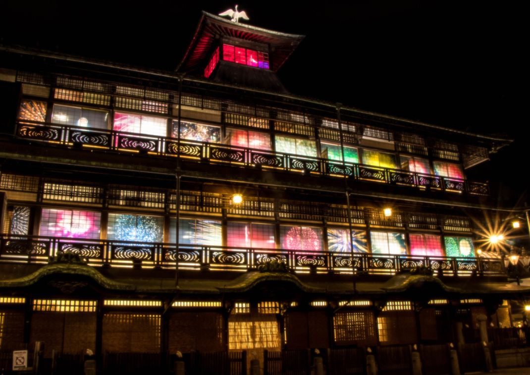 Edificio histórico japonés iluminado por la noche con luces de colores brillando a través de sus ventanas