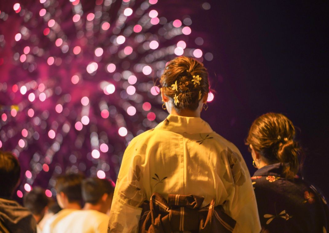 Mujeres en yukata viendo fuegos artificiales en verano
