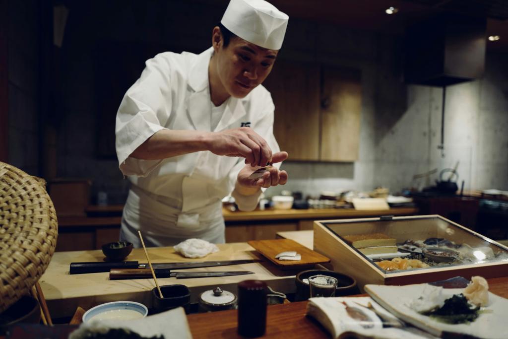 Cocinero japonés es sashimi delante de la barra del mostrador en un restaurante de sushi japonés