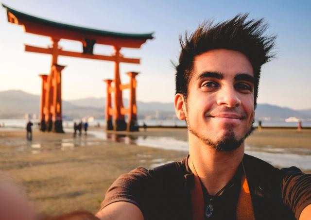 Hombre de pie frente a una puerta torii roja japonesa en Japón