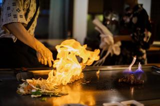 Chef preparando comida teppanyaki con ternera a la parrilla y verduras