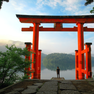 Turista ante la puerta roja torii del santuario de Hakone, situado en el lago Ashi (Japón).