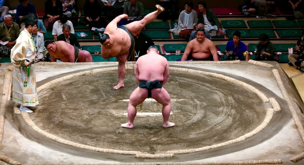 Luchadores de sumo japoneses preparándose para un combate en el ring, vistiendo los tradicionales mawashi.