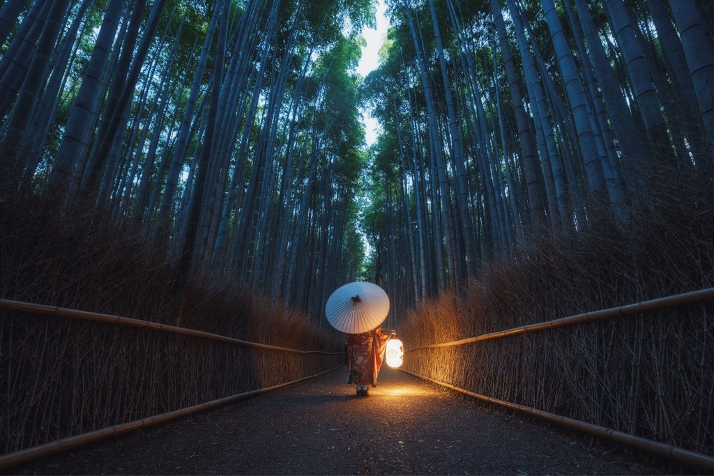 Mujer en kimono paseando por el bosque de bambú de Arashiyama en Kioto al atardecer