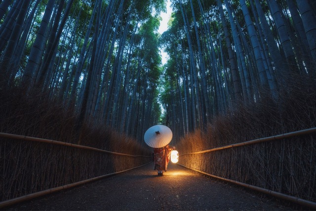 Mujer en kimono paseando por el bosque de bambú de Arashiyama en Kioto al atardecer