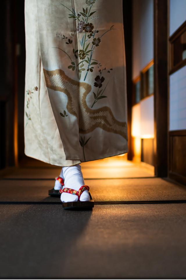 Mujer con kimono paseando por un ryokan tradicional con esteras tatami y puertas shoji.