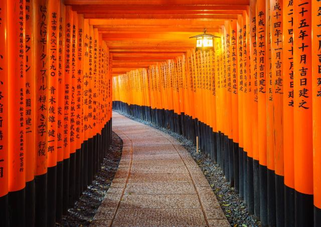 Una puerta roja torii tradicional japonesa con escritura negra en el Santuario Fushimi Inari, Kioto, Japón